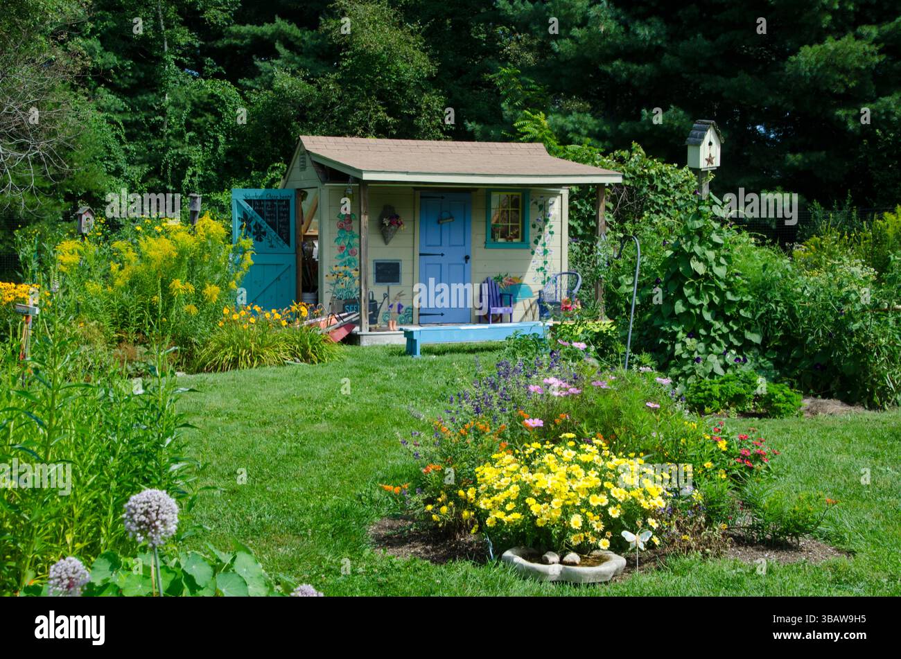 Cute Painted shed in children's garden for tool storage in a blooming summer flowers at the community Garden, Yarmouth ME, USA Stock Photo