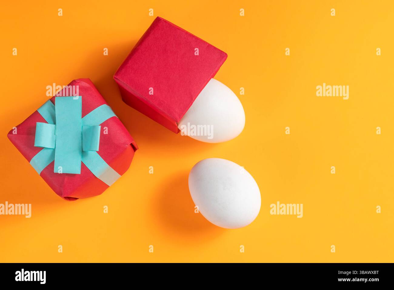 Brightly colored gift boxes and white eggs were arranged on a vibrant orange surface depicting Easter joy. Stock Photo
