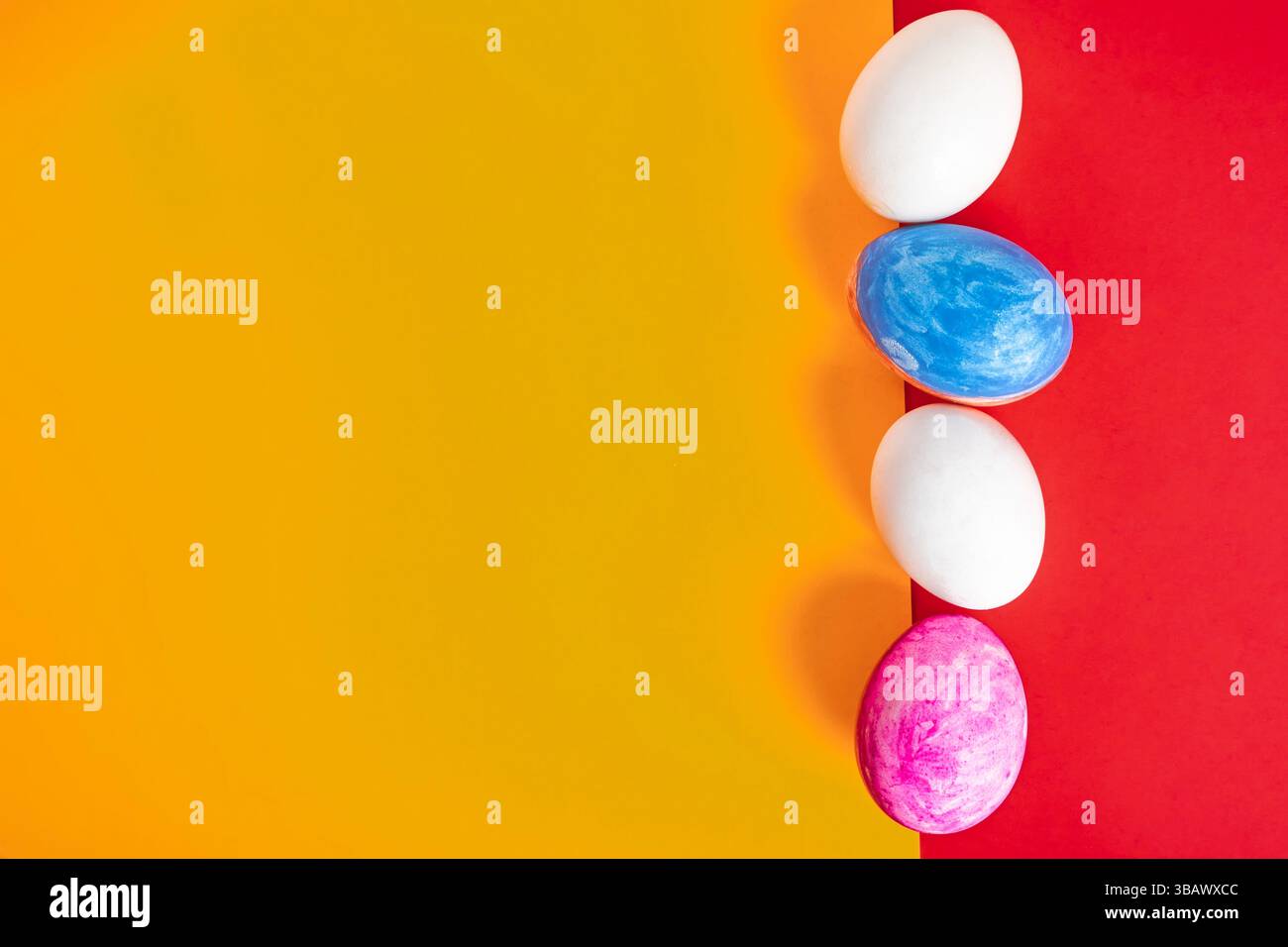 Colorful Easter eggs arranged in a row on a split red and yellow background. Perfect for spring themes. Stock Photo