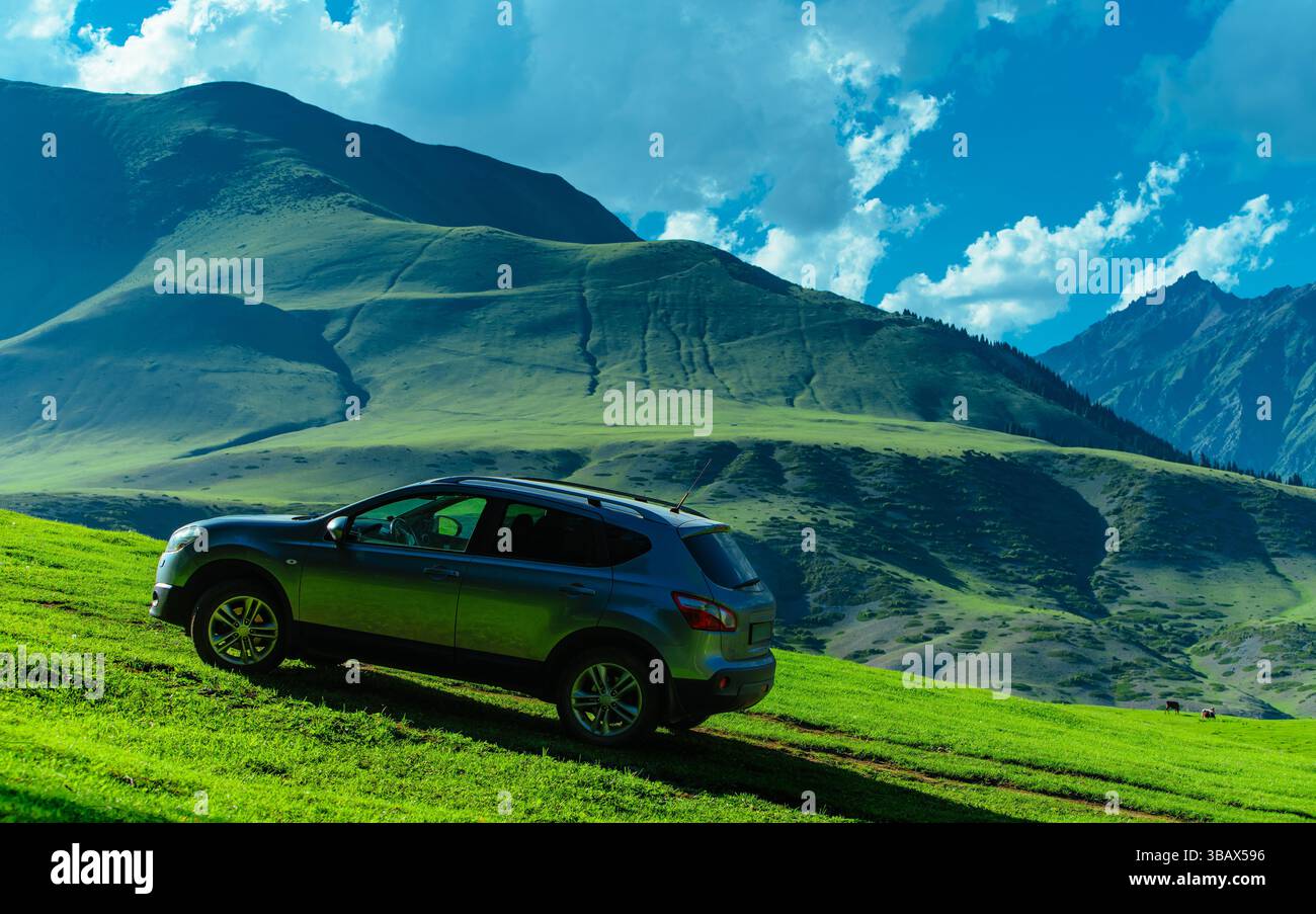 Modern car on a green hill in a picturesque mountains valley, travel concept Stock Photo