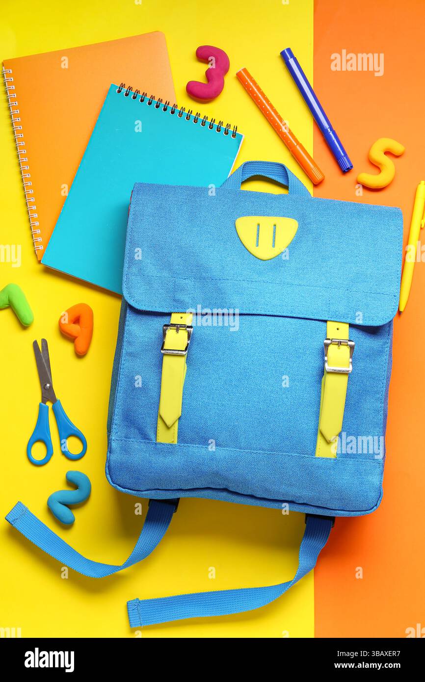 Stylish school backpack with different stationery on color background Stock Photo