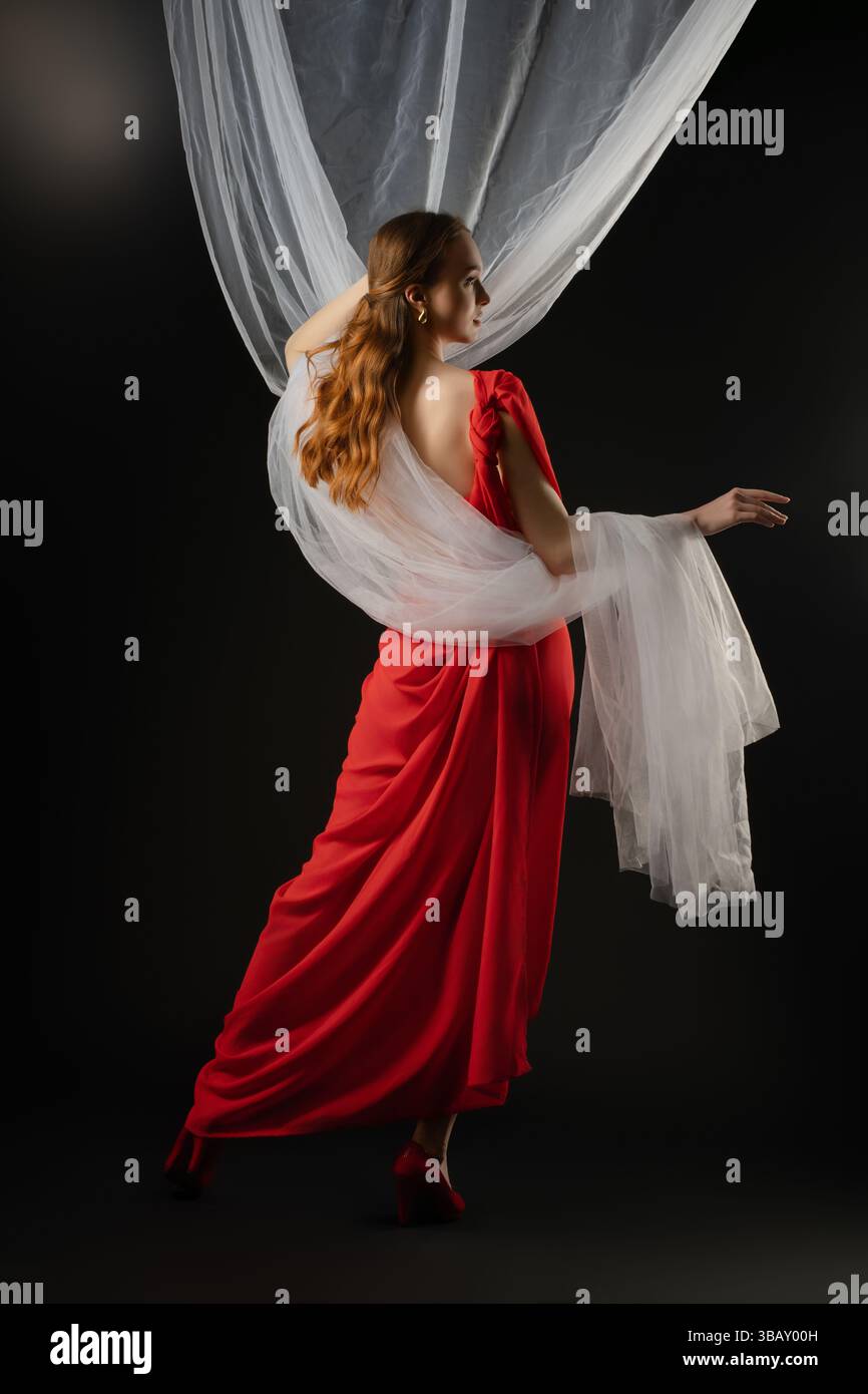 Woman in a red dress poses elegantly in a studio, showcasing emotion ...