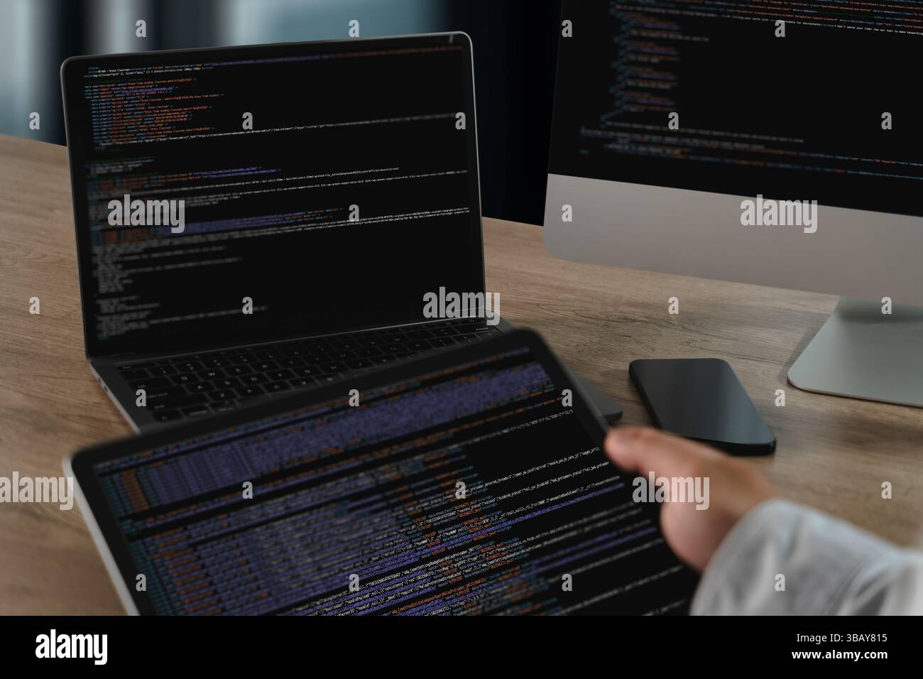 A website programming person working with multiple screens displaying code and data, modern office setting, showing focus and technical activity Stock Photo