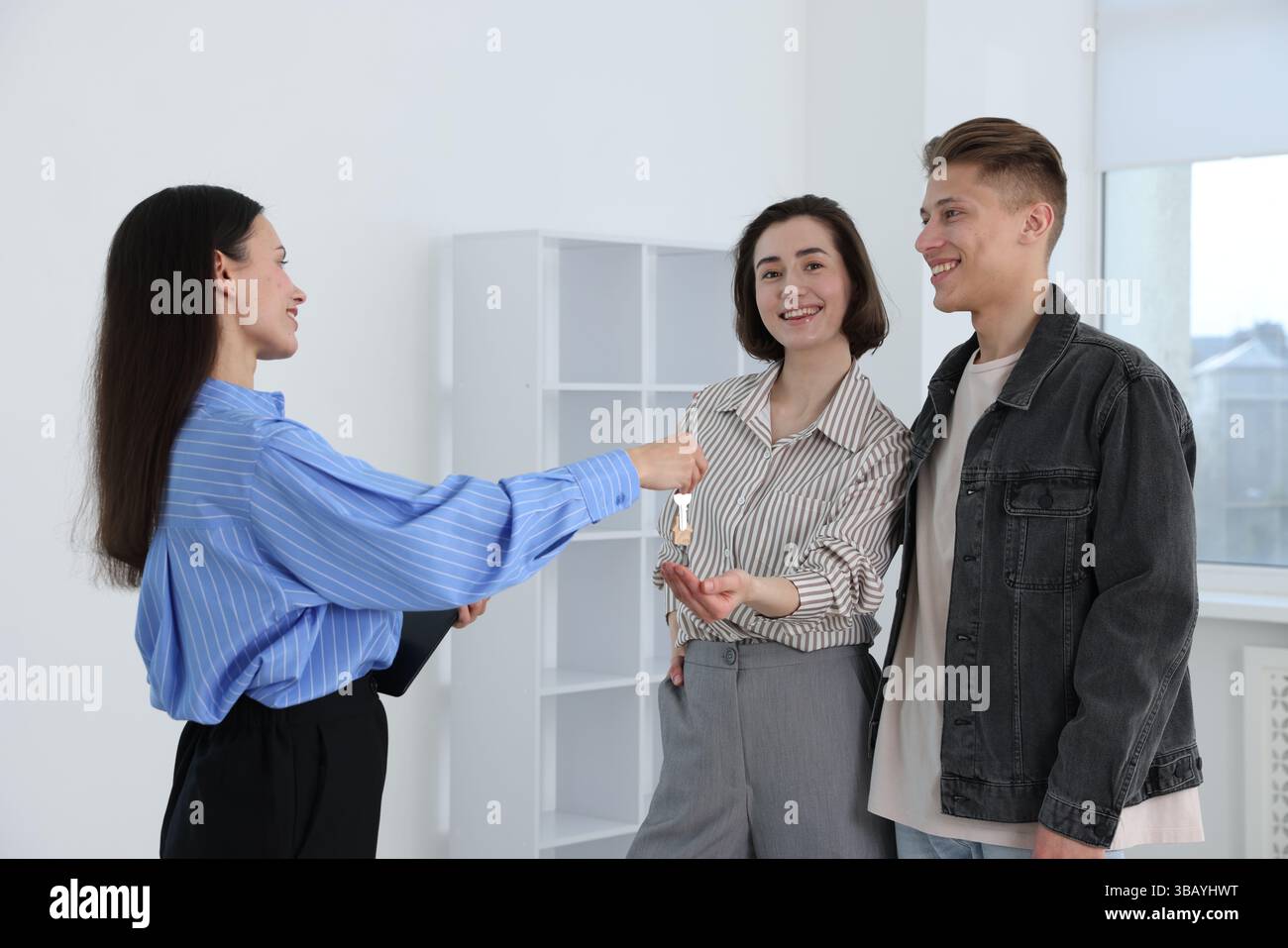 Real estate agent giving house key to new owners indoors Stock Photo ...