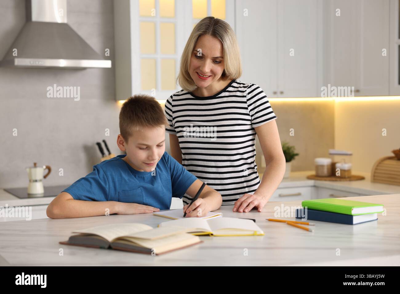 Mother and son doing homework at table indoors Stock Photo - Alamy
