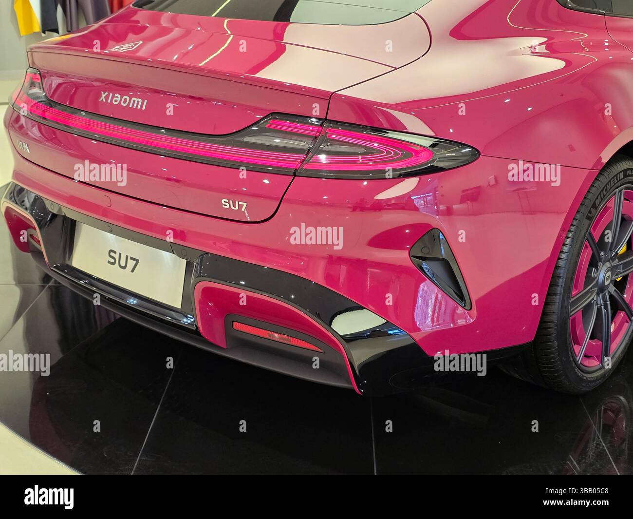 Su7 Rear Rear view of a bright magenta Xiaomi SU7 electric car in a showroom ...