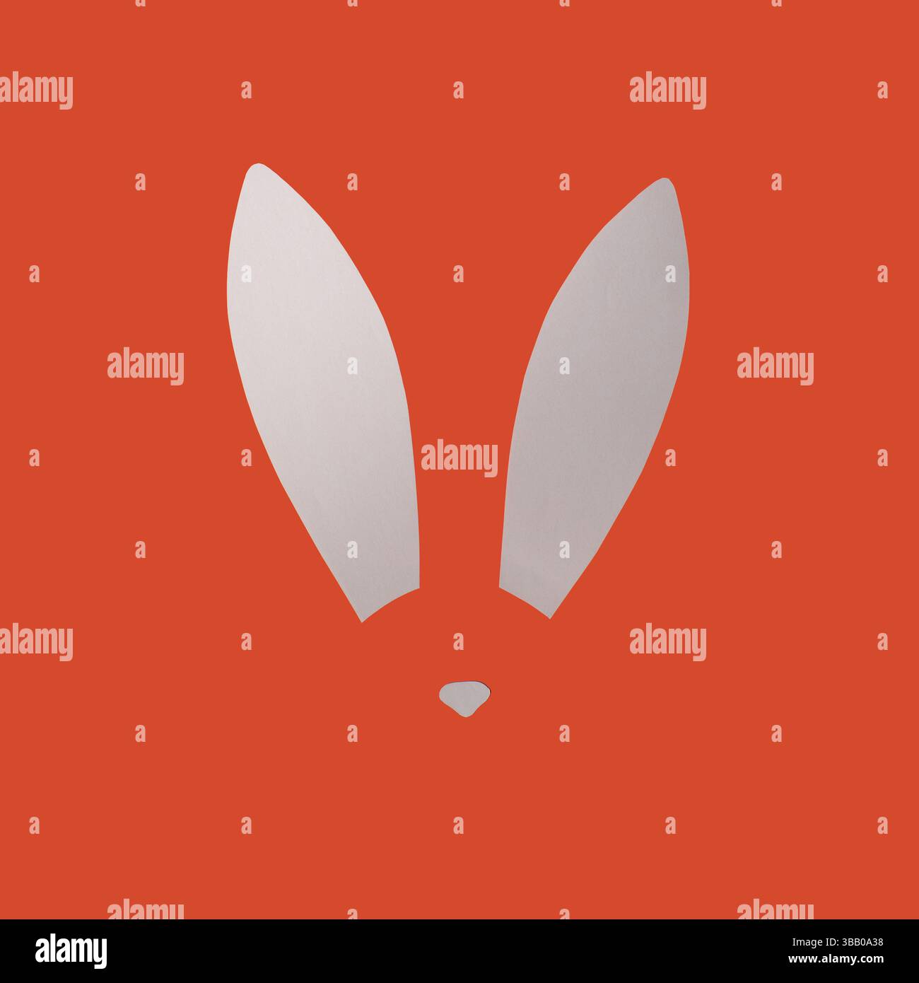 Rabbit ears from white paper on orange background. Easter minimal concept. Flat lay. Stock Photo