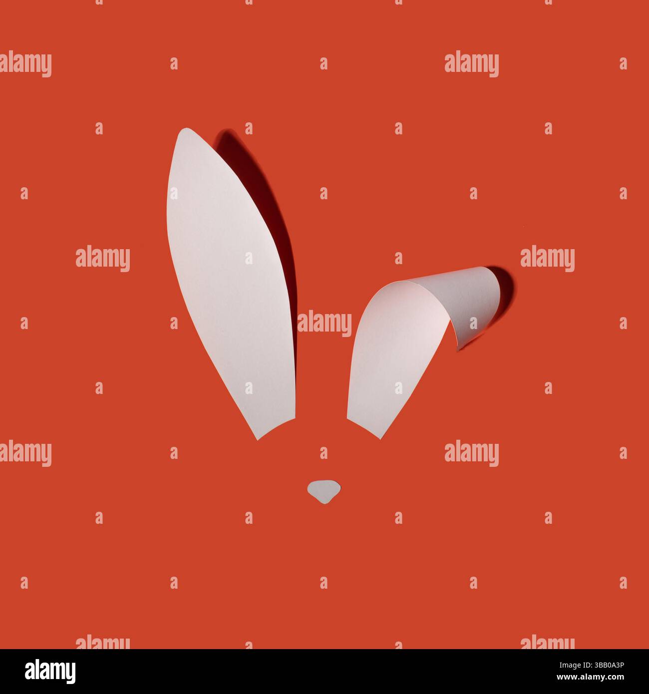 Rabbit ears from white paper on orange background. Easter minimal concept. Flat lay. Stock Photo