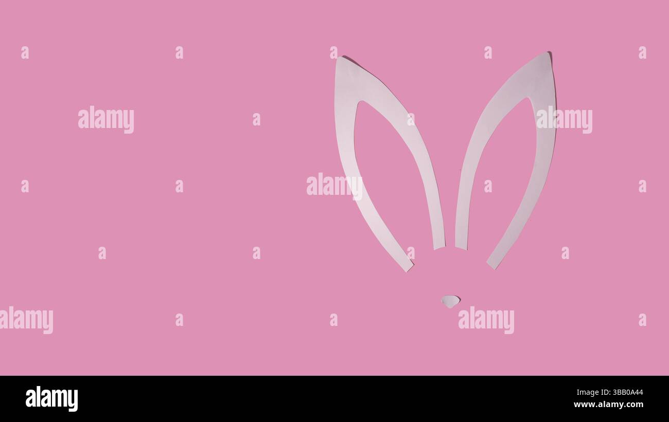 Rabbit ears from white paper on pink background. Easter minimal concept. Flat lay. Stock Photo