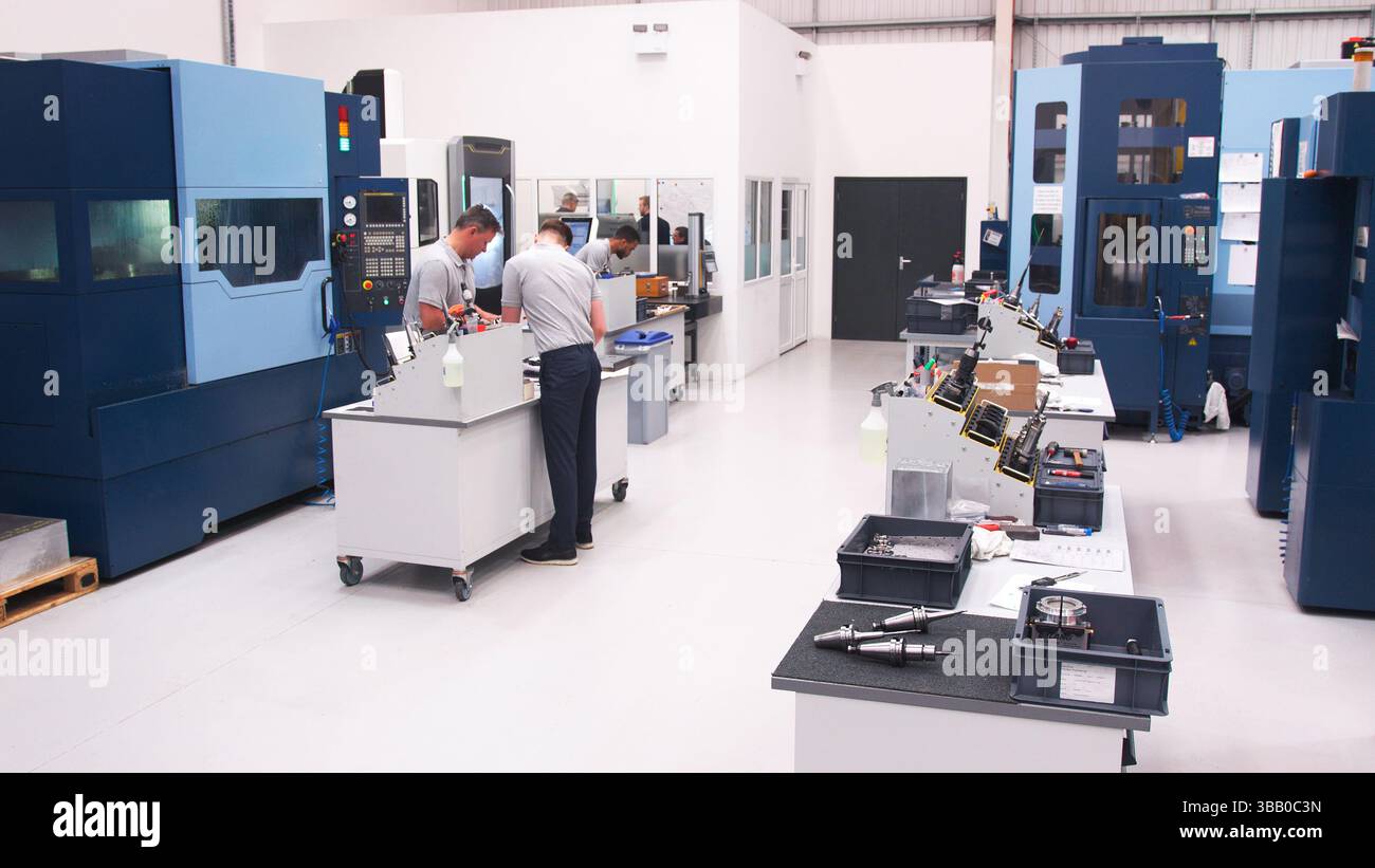 Busy Engineering Workshop With Workers Using CNC Machinery Stock Photo