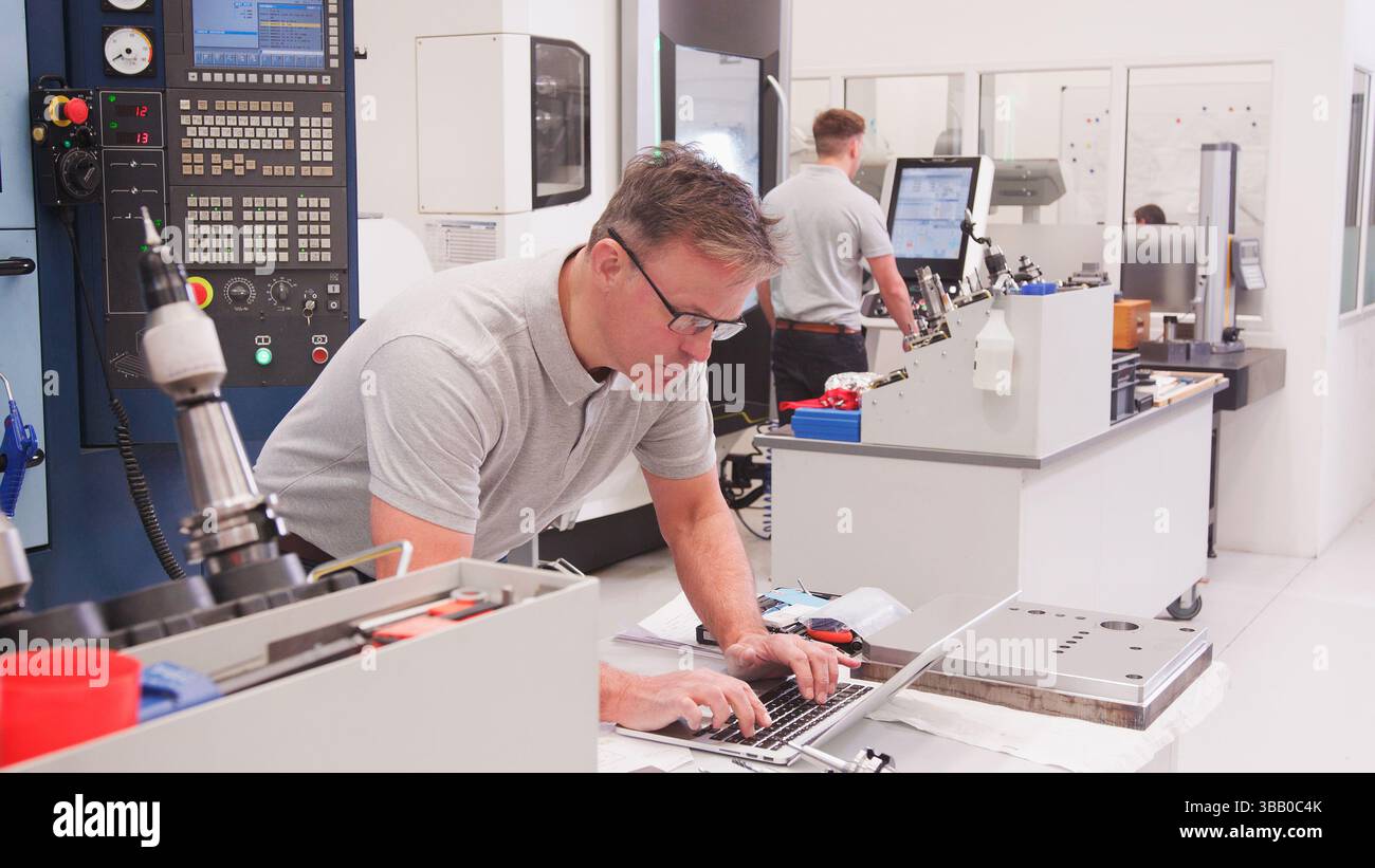 Mature Male Engineer In Factory Using CAD Programming Software On Laptop Stock Photo