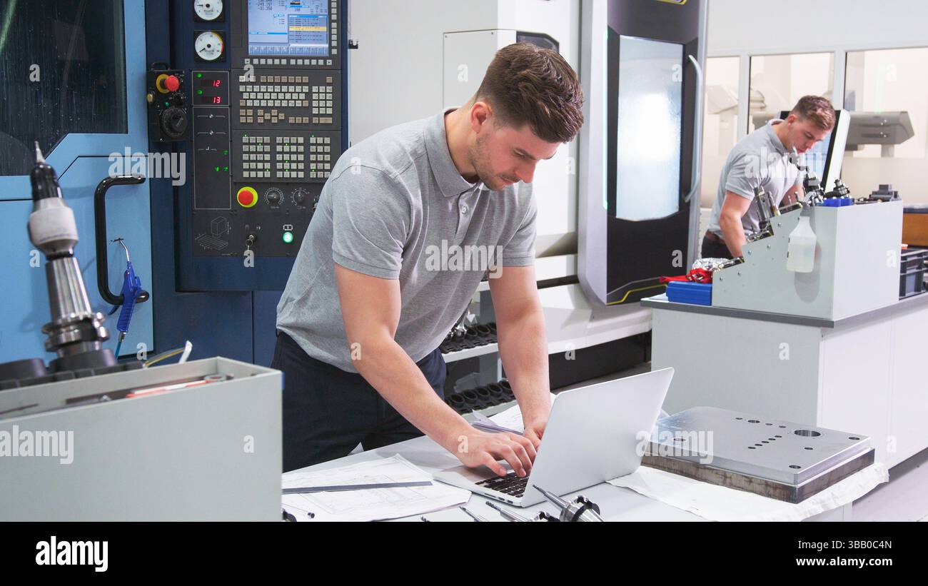 Male Engineer In Factory Using CAD Programming Software On Laptop Stock Photo