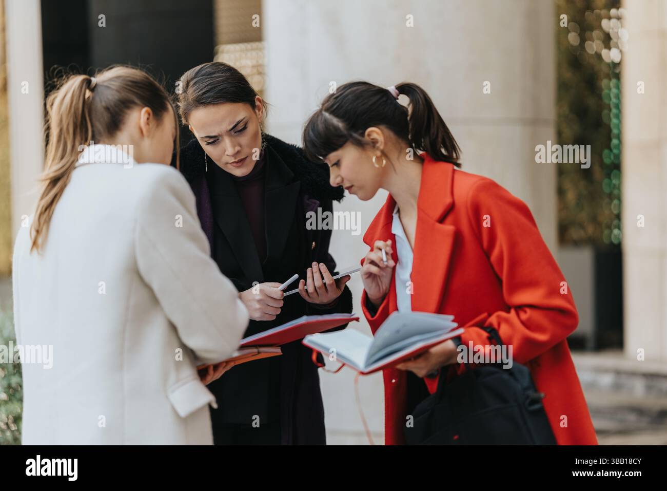 Three Businesswomen Collaborating Outdoors with Documents and Notes Stock Photo