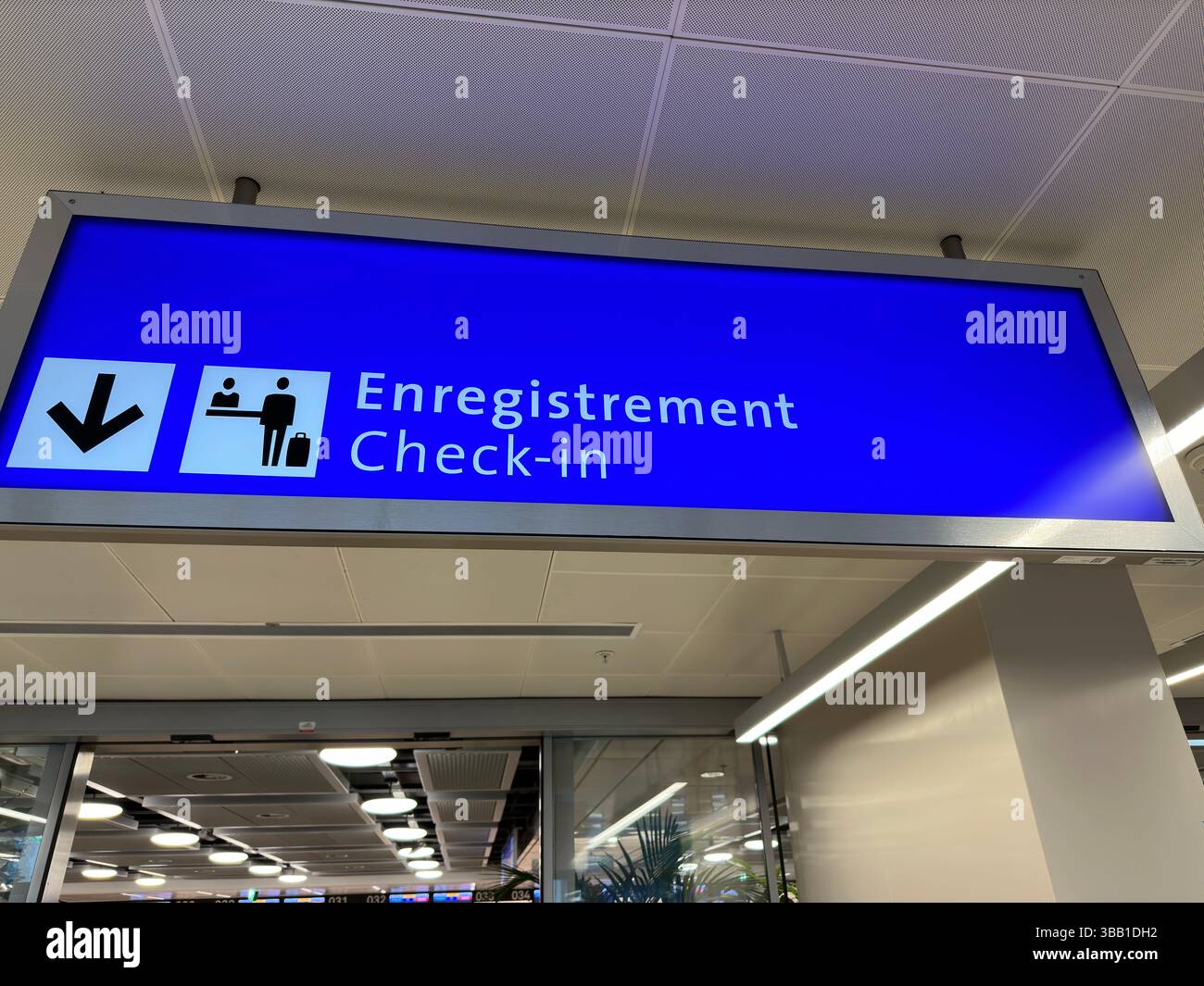 Airport check-in sign in both French and English hangs over a doorway. - Smartphone Captured Stock Image