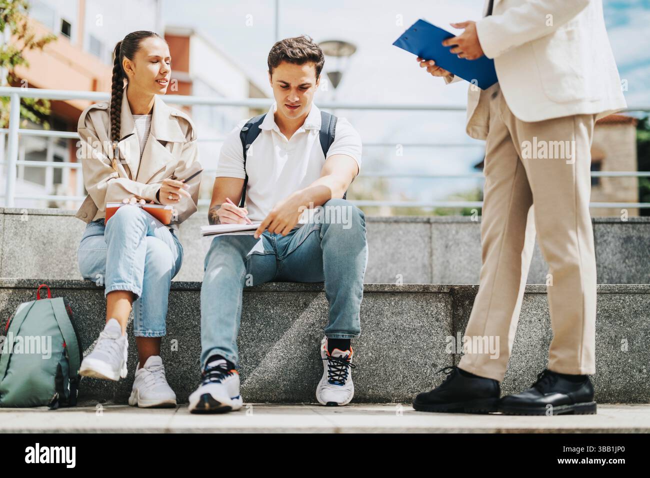 High school students collaborating outdoors with professor assisting Stock Photo