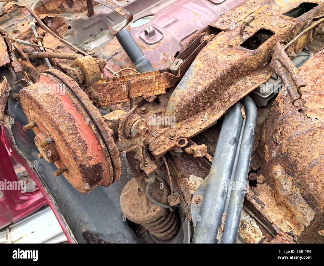 Old and forgotten, the rusted components of a vintage car lie scattered ...