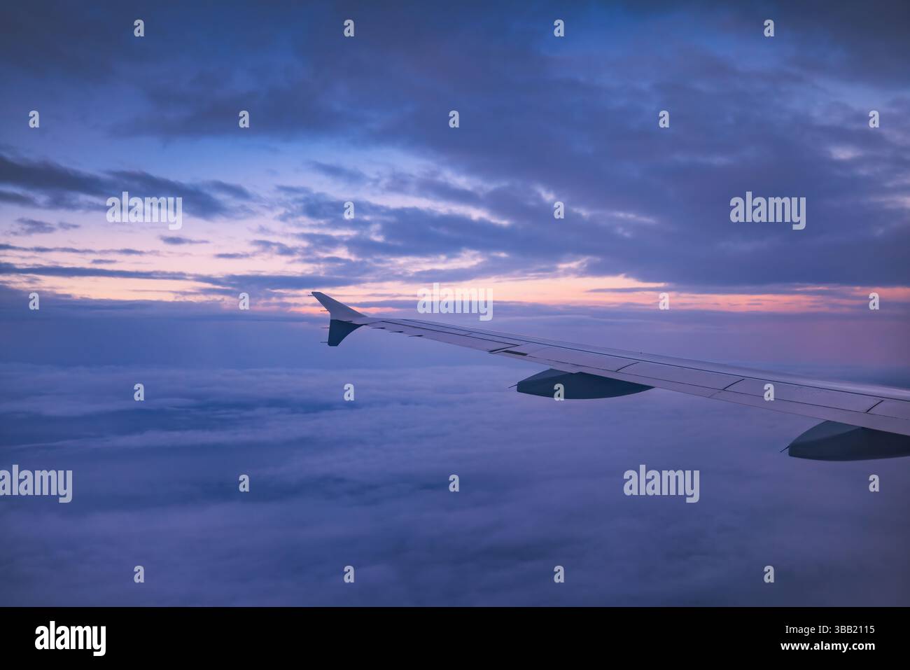 Airplane flying over color sky clouds during scenic sunset or sunrise ...