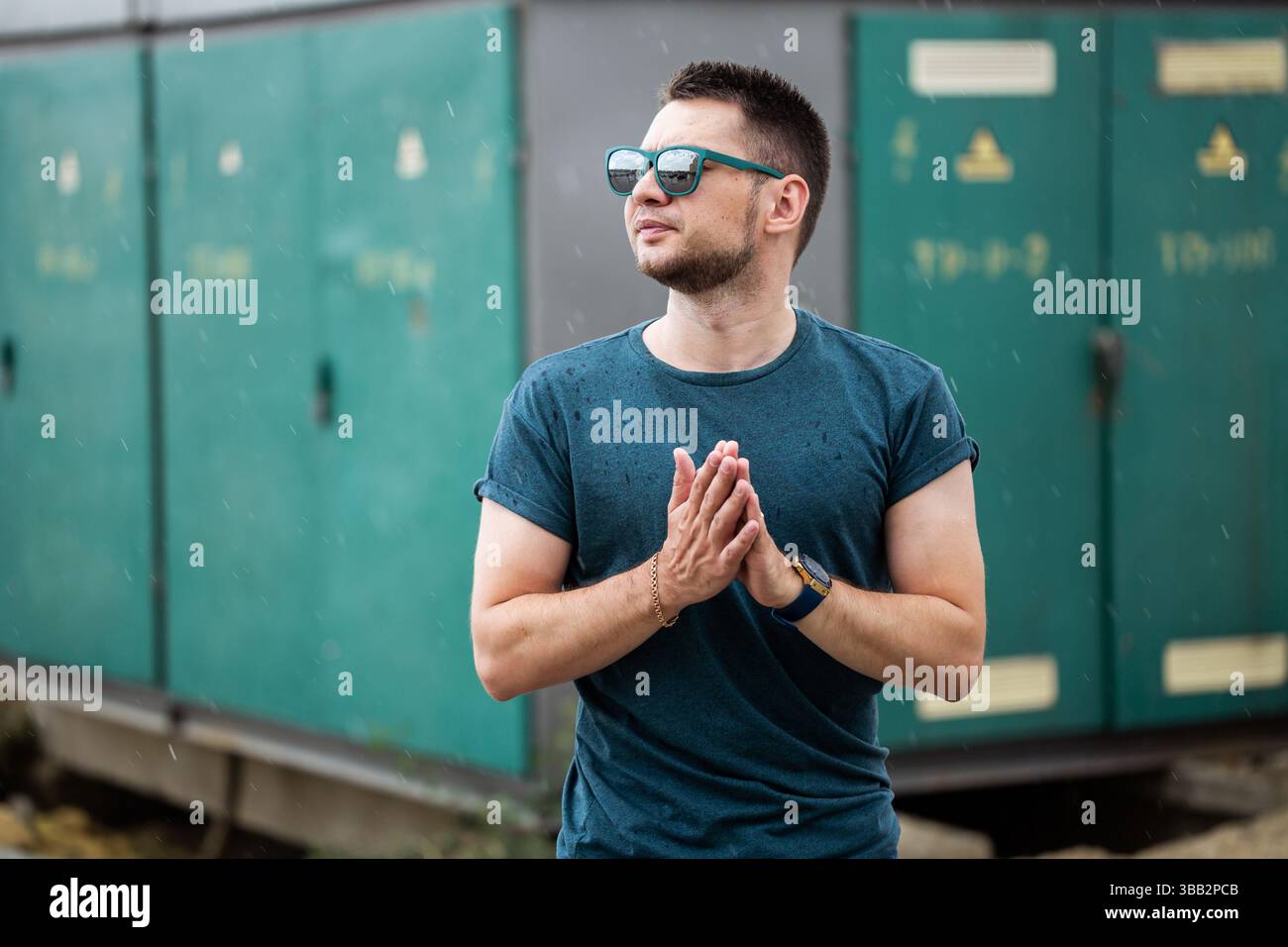 A young man stands confidently outdoors, wearing stylish sunglasses ...