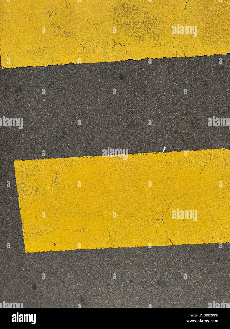 Minimal close-up of a yellow pedestrian crossing line on asphalt. The ...