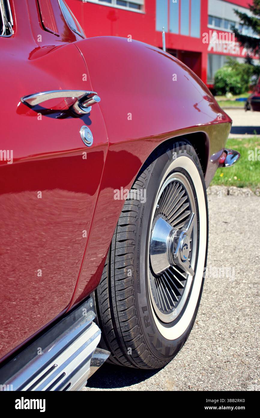 Close-up of rear side and wheel of a red Chevrolet Corvette Sting Ray classic car with chrome details and whitewall tires. Stock Photo