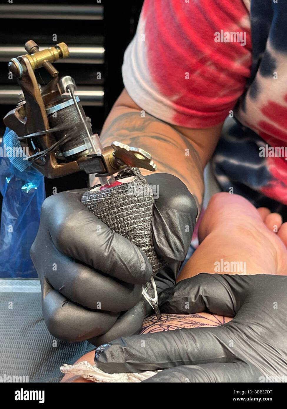 Tattoo artist hard at work tattooing a mandala - Smartphone Captured Stock Image