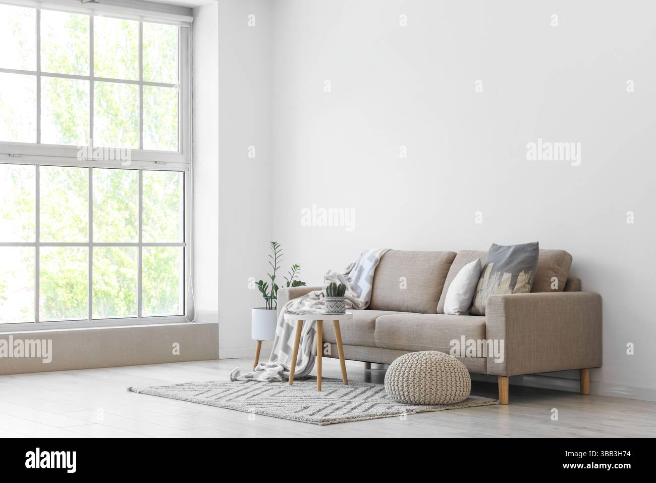 Interior of light living room with grey sofa, table and pouf Stock ...