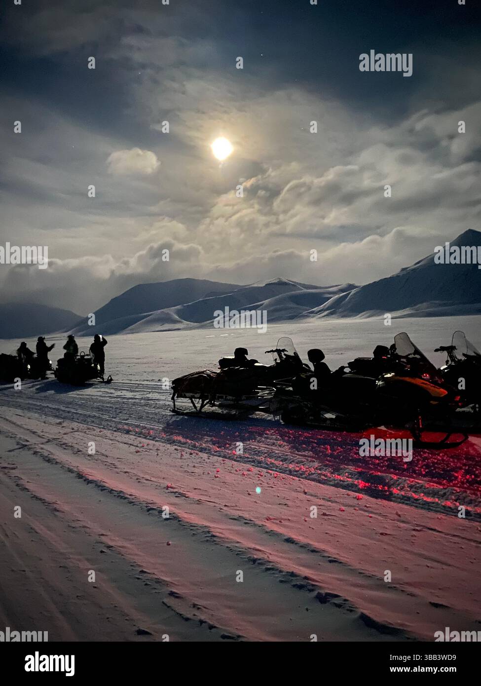 Snowmobiles and people under full moon in Arctic winter, Svalbard - Smartphone Captured Stock Image