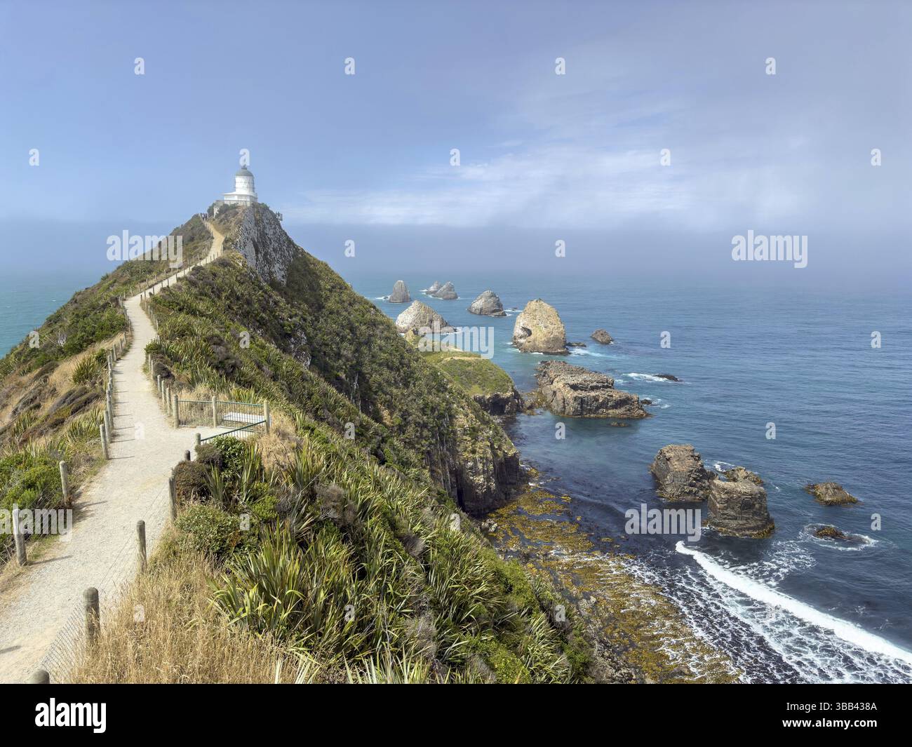 Nugget Point Lighthouse with Nugget Rocks in front of a blue sky, South ...
