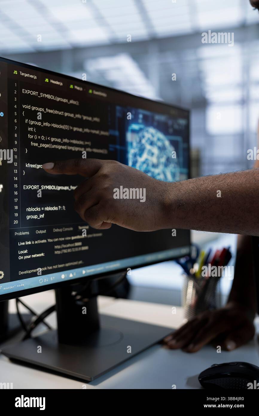 System administrator using machine learning applications to optimize server farm operations. IT expert pointing to PC monitor, implementing server virtualization in data center facility Stock Photo