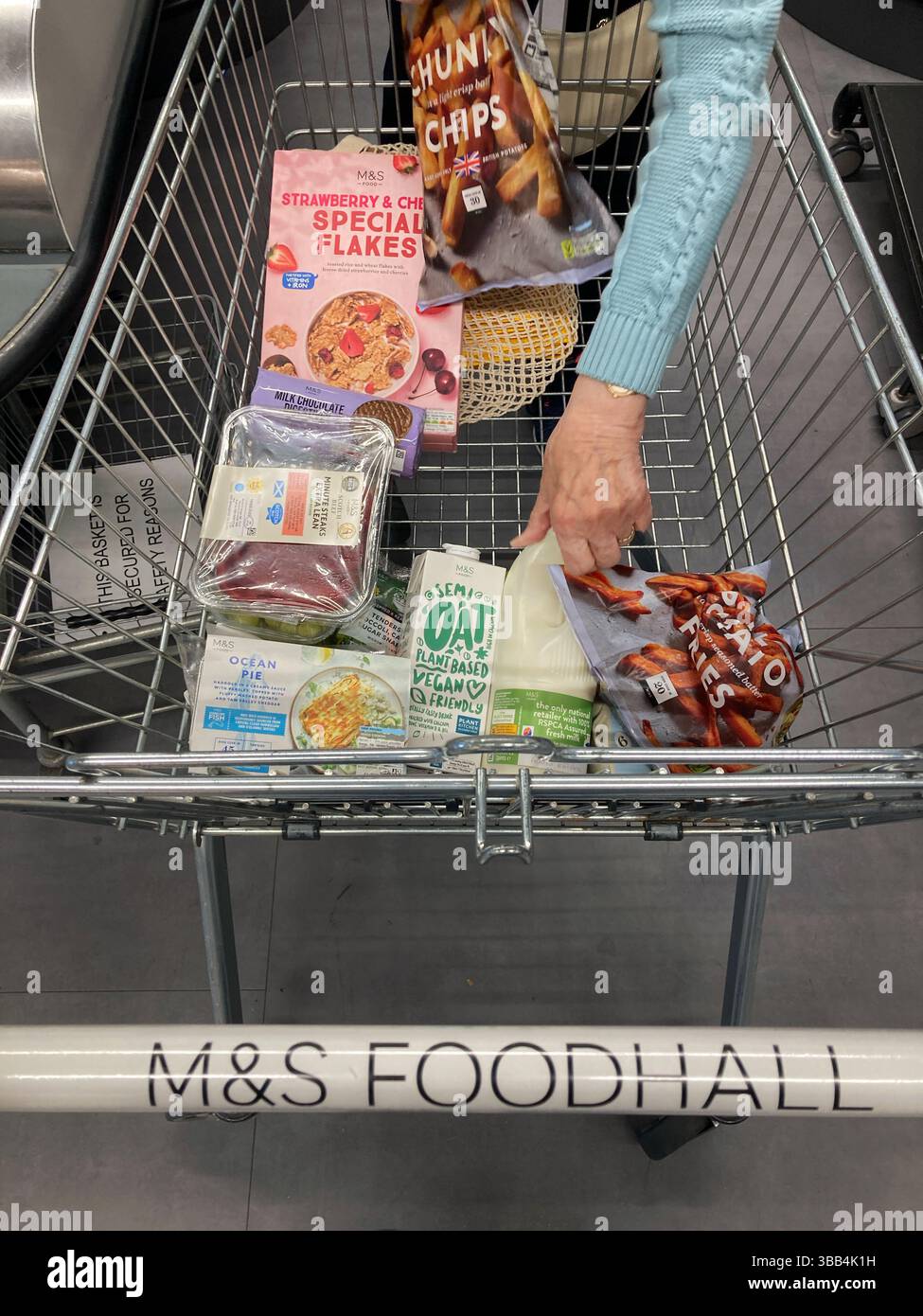 At checkout with Shopping trolley unloading groceries in a Marks and Spencer food hall - Smartphone Captured Stock Image