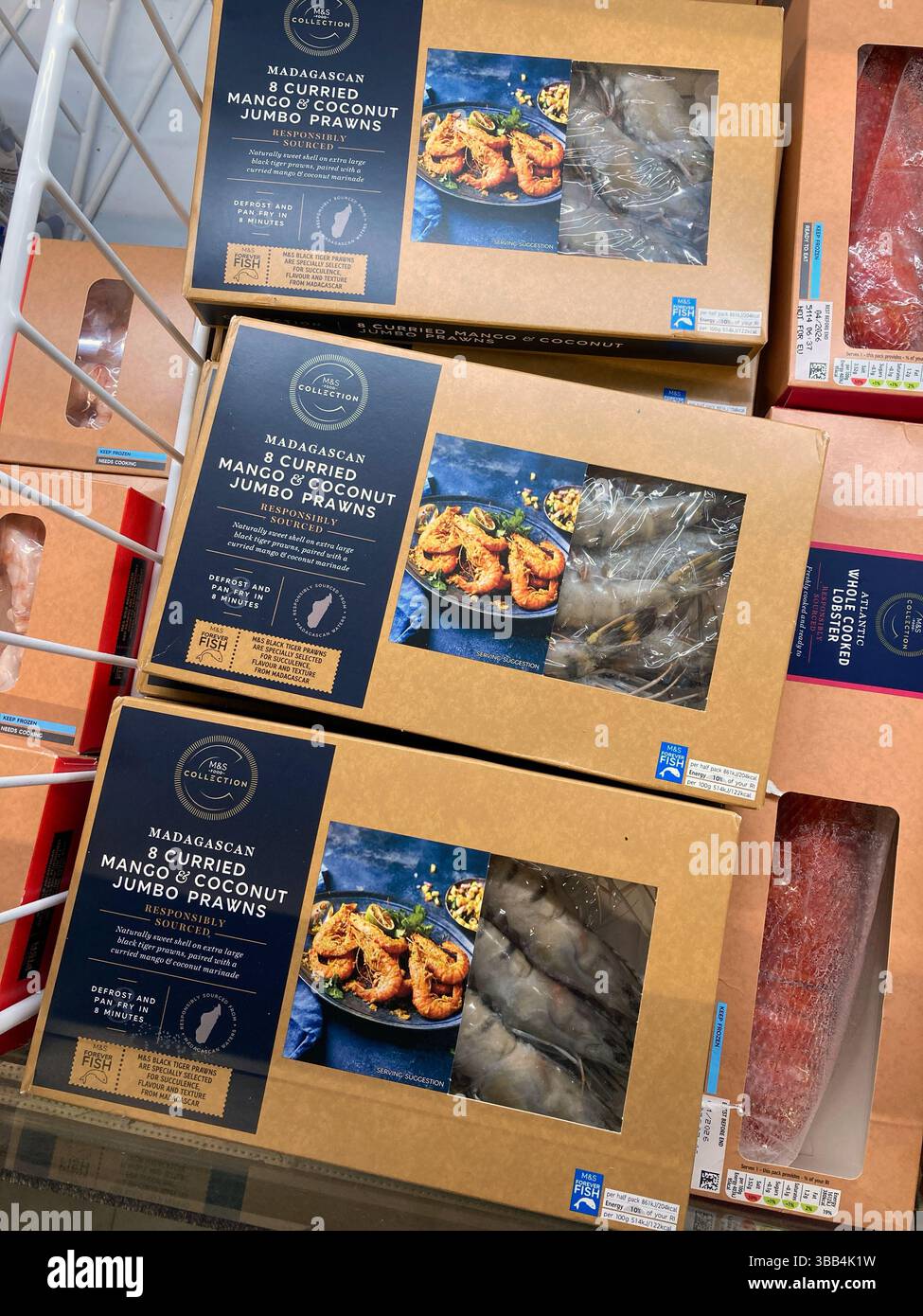 Marks and Spencer own brand boxes of frozen Curried Mango and Coconut Prawns for sale in freezer cabinet, UK Stock Photo