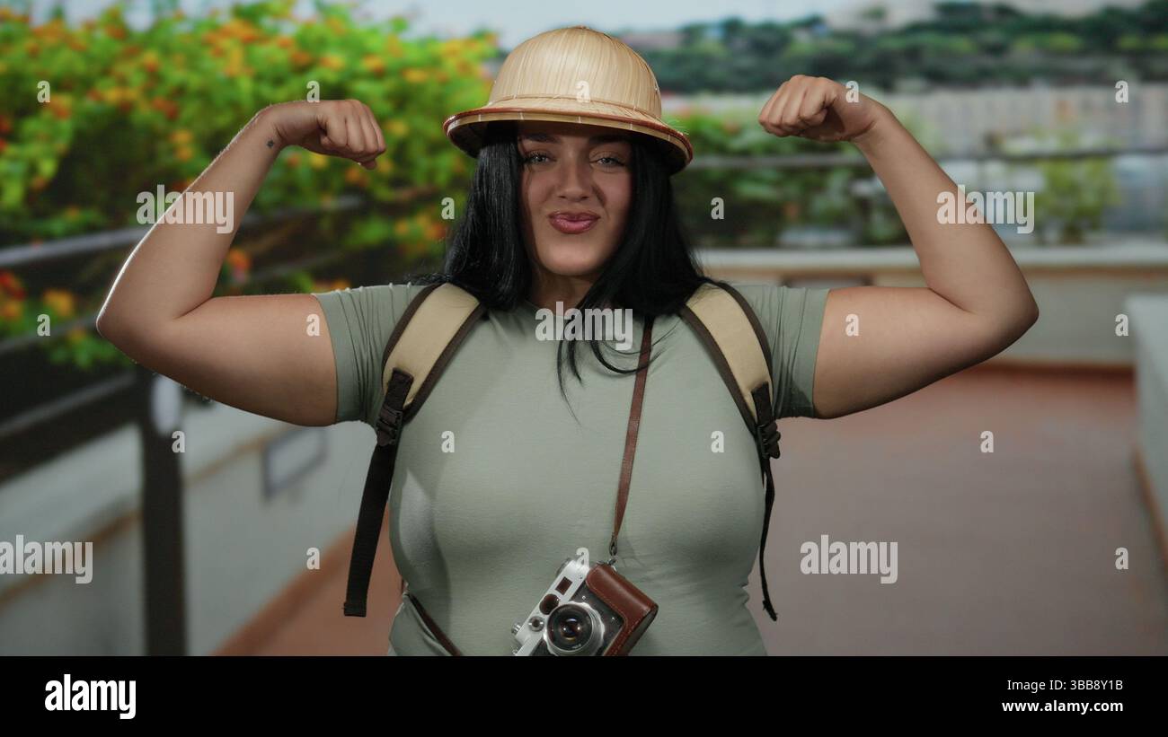 Woman tourist flexing in outdoor city street wearing hat with backpack ...
