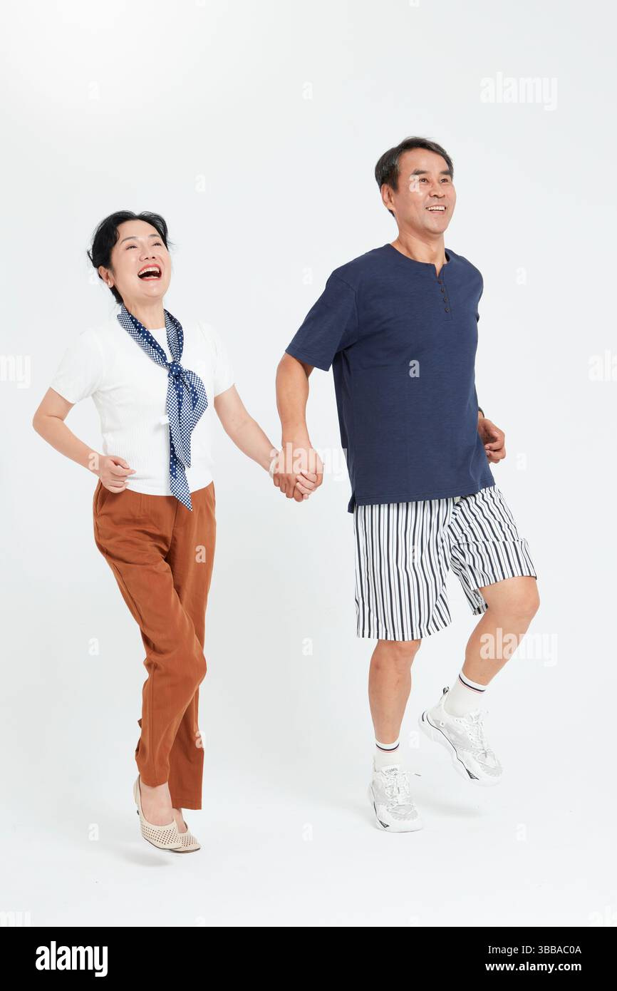 elderly couple running hand in hand​ Stock Photo
