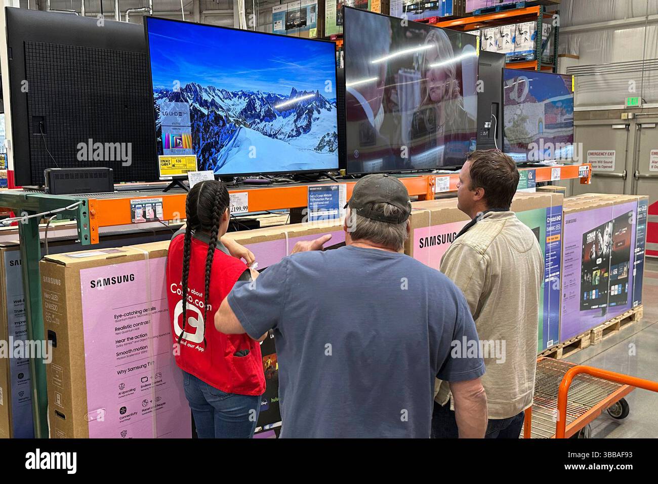 Shoppers consider a large-screen television with the help of a sales ...