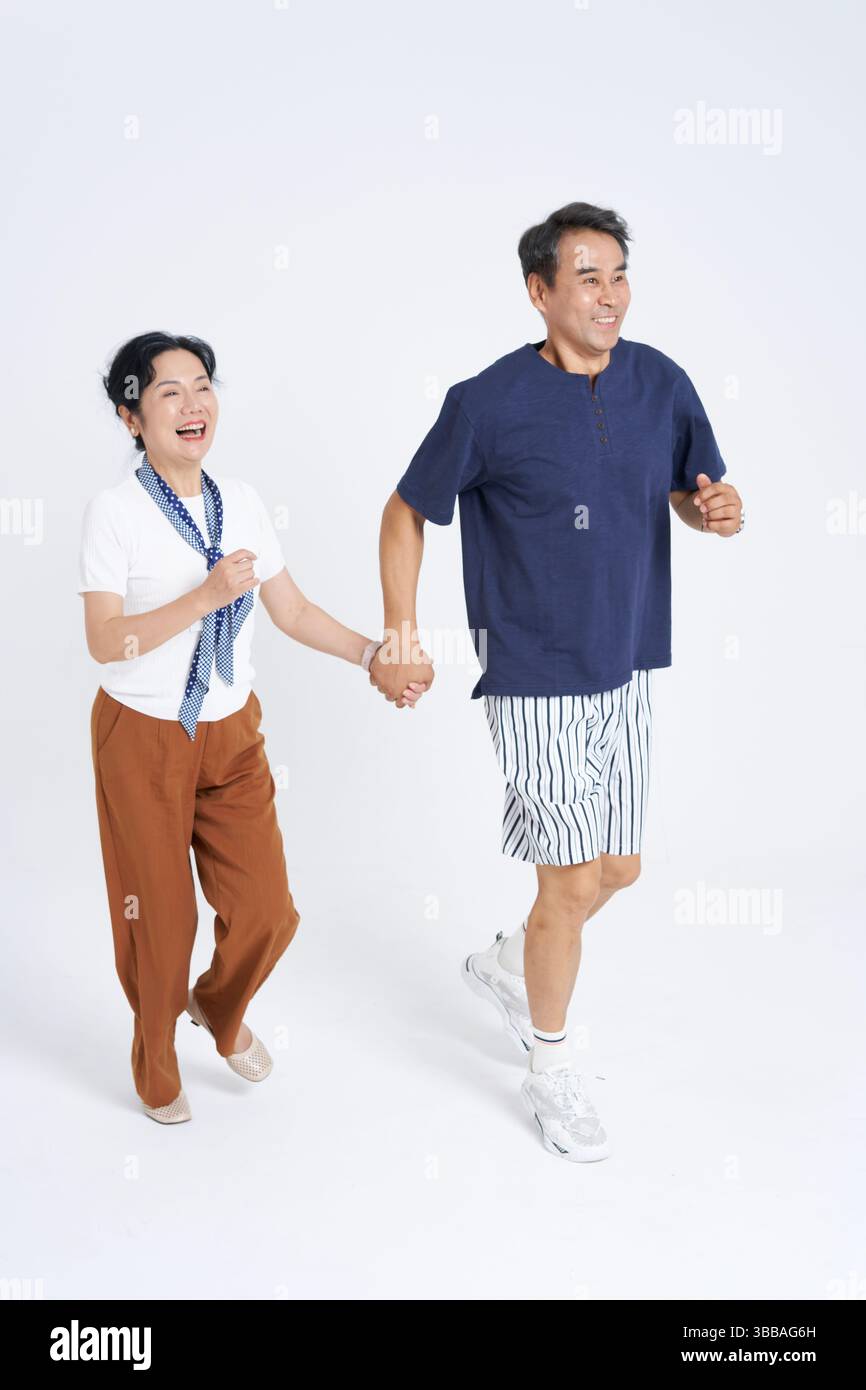 elderly couple running hand in hand​ Stock Photo