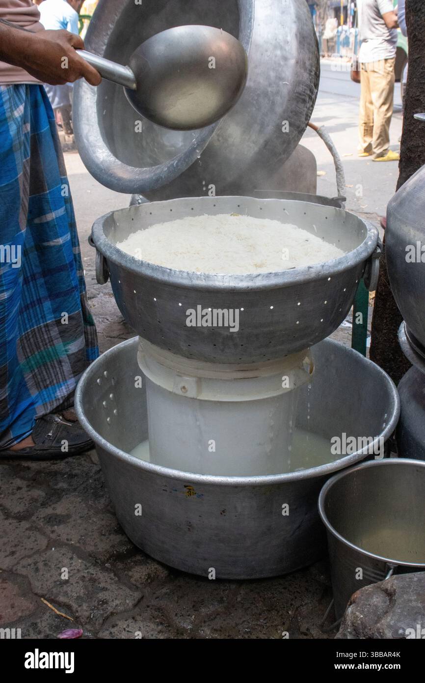 rice being cooked in the traditional way on the dirty street in Kolkata ...