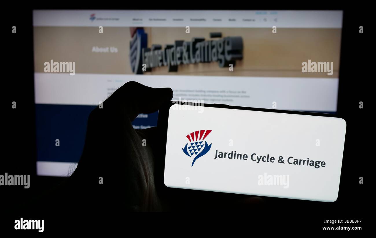 Stuttgart, Germany - 01-03-2024: Person holding mobile phone with logo of Singaporean company Jardine Cycle Carriage Limited on screen Stock Photo