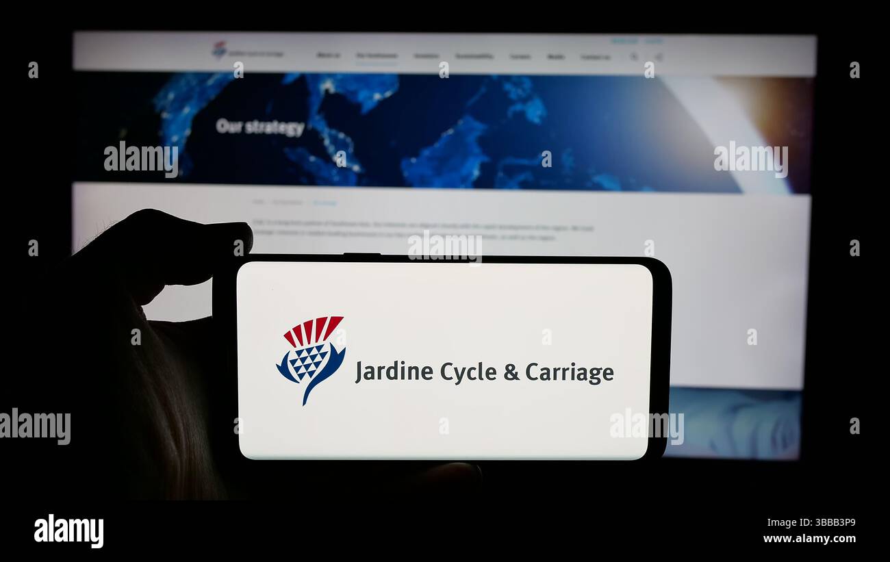 Stuttgart, Germany - 01-03-2024: Person holding cellphone with logo of Singaporean company Jardine Cycle Carriage Limited on screen Stock Photo