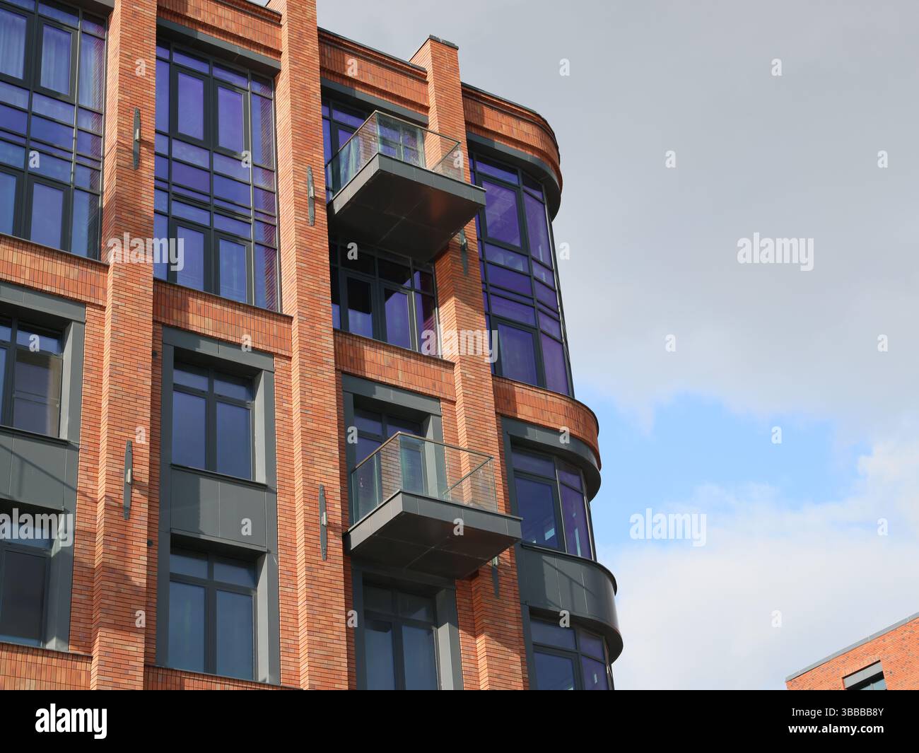 A modern brick building with elegant balconies and large windows that ...