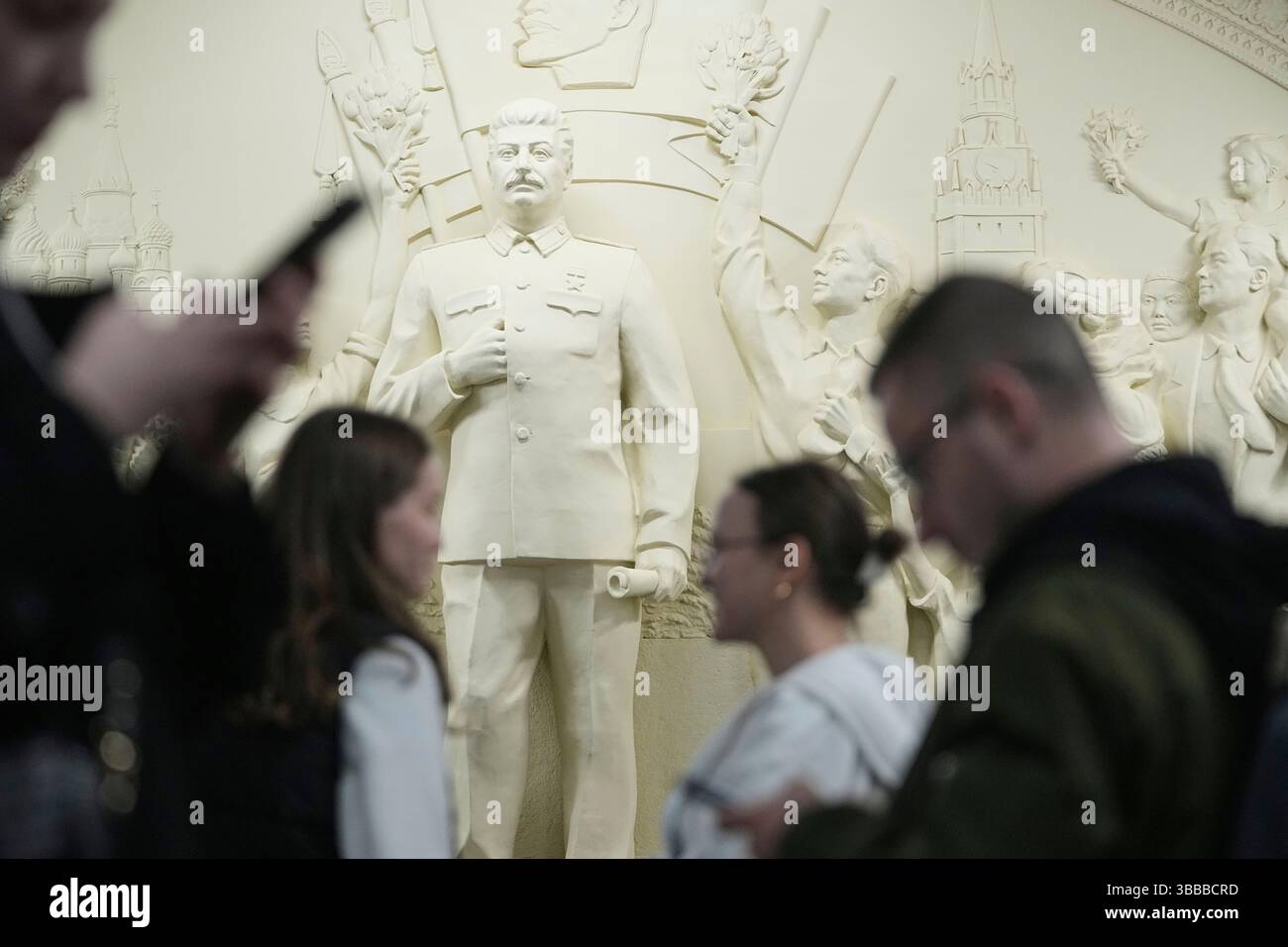 People pass by a restored 1960 bas-relief 