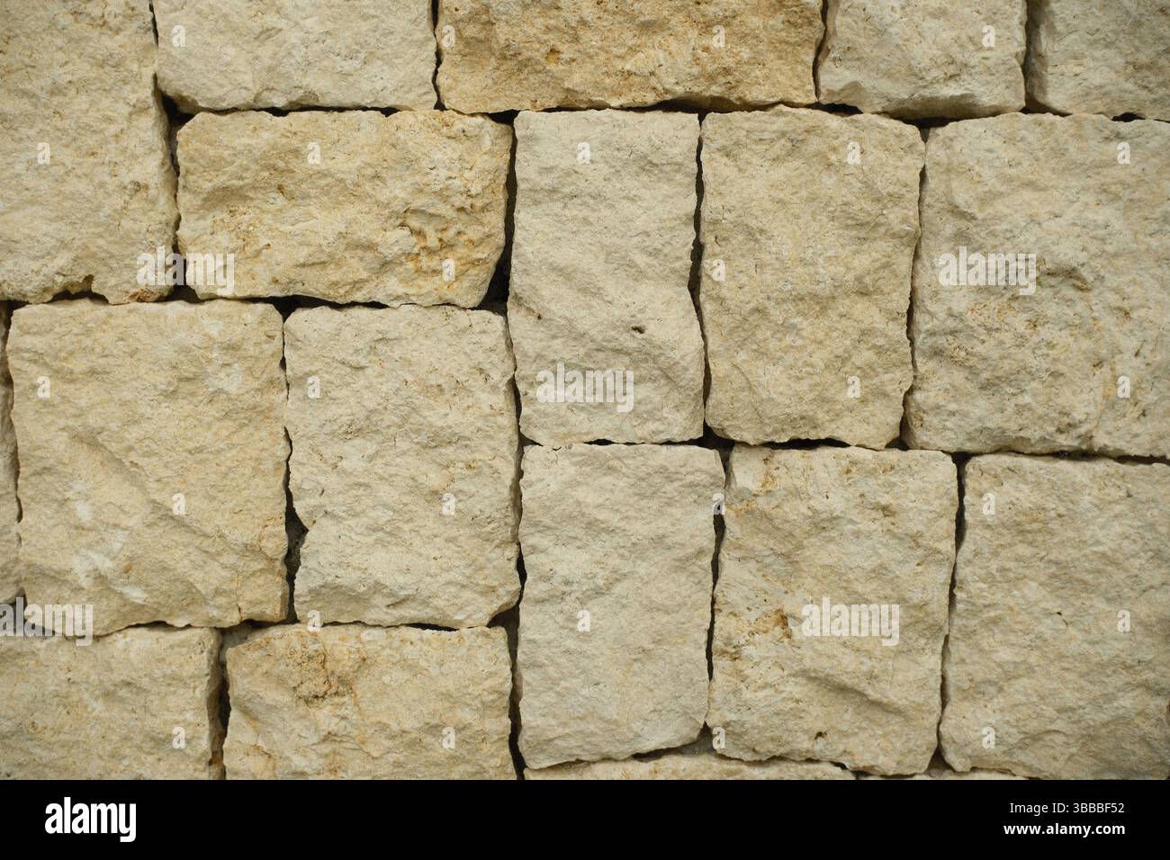 A close up view of a textured rectangular limestone block stone wall Stock Photo
