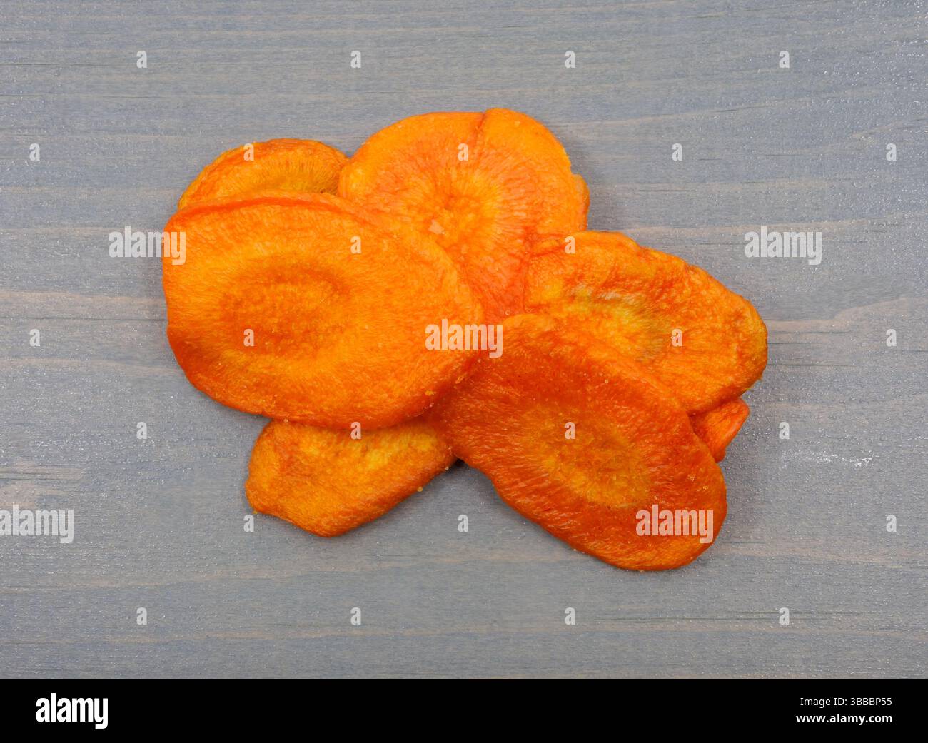 Dried carrot chips on a gray painted background top view. Stock Photo