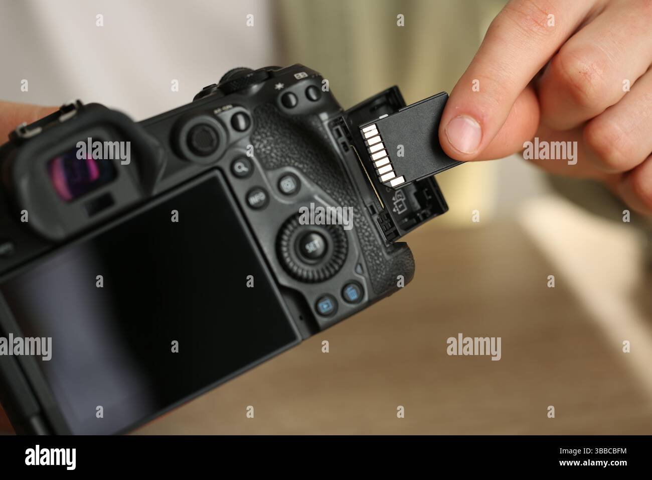 Man inserting SD memory card into photo camera, closeup Stock Photo
