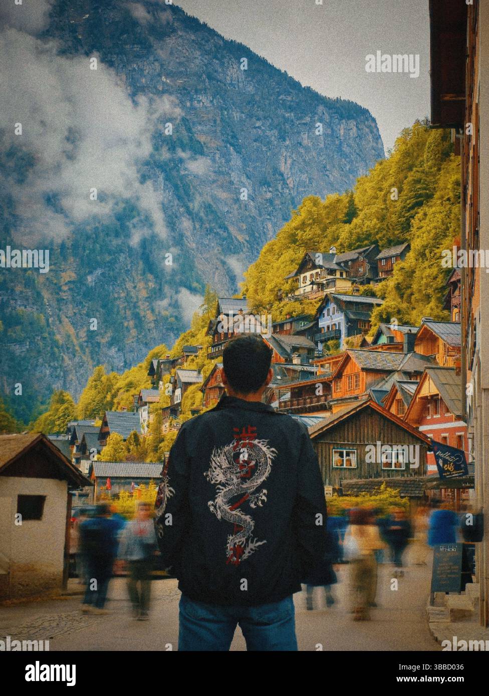 Rear view of a man standing in front of the picturesque mountain village of Hallstatt, Austria. - Smartphone Captured Stock Image