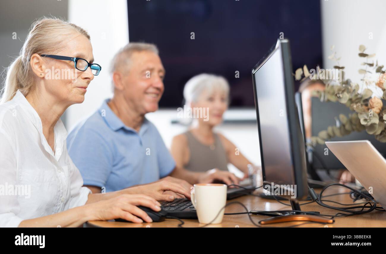 Old woman learning computer programs in training room Stock Photo