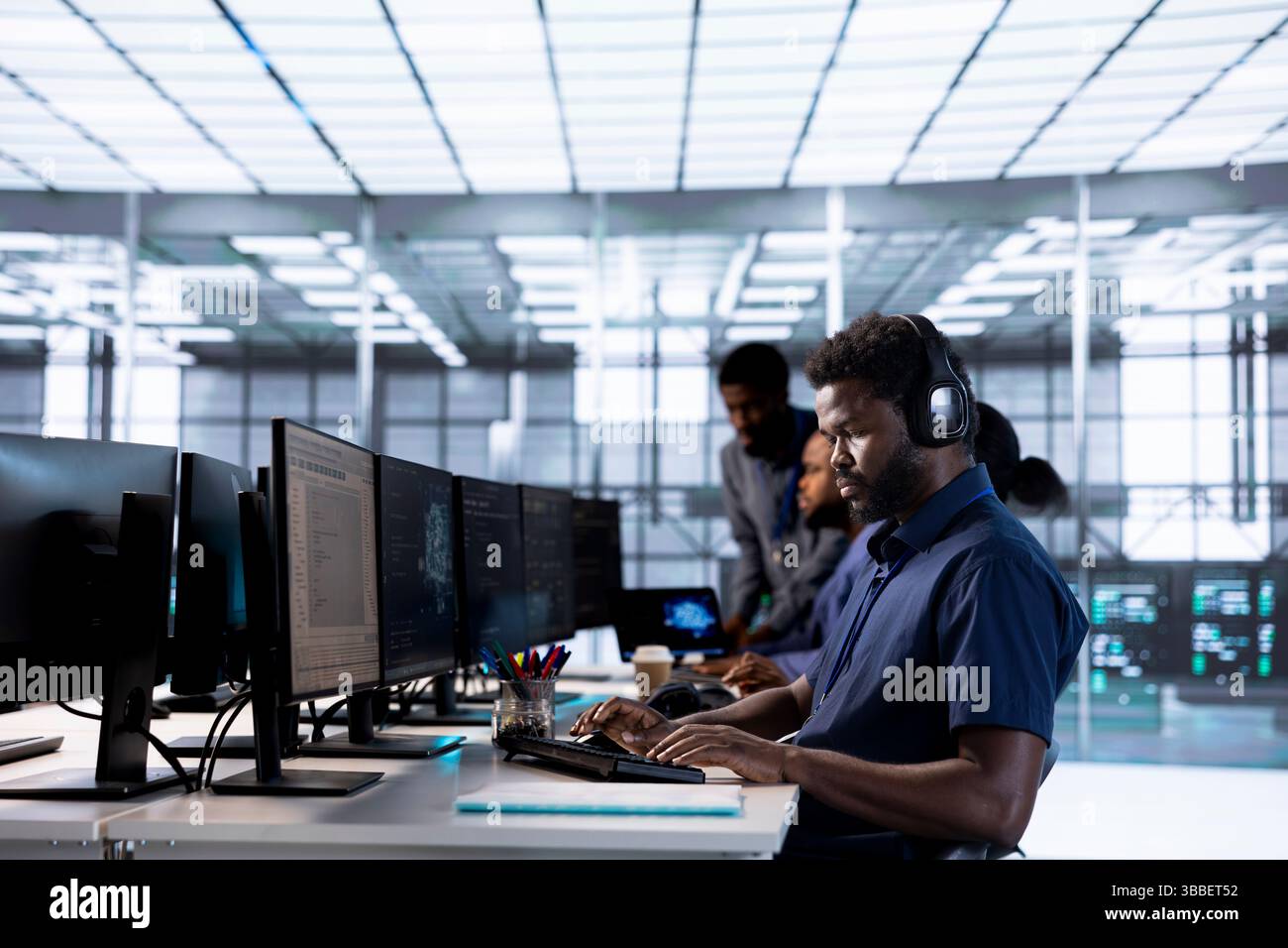Man in data center workplace hearing songs in headset while using programming languages to build applications. Server hub software developer listening music, debugging code Stock Photo