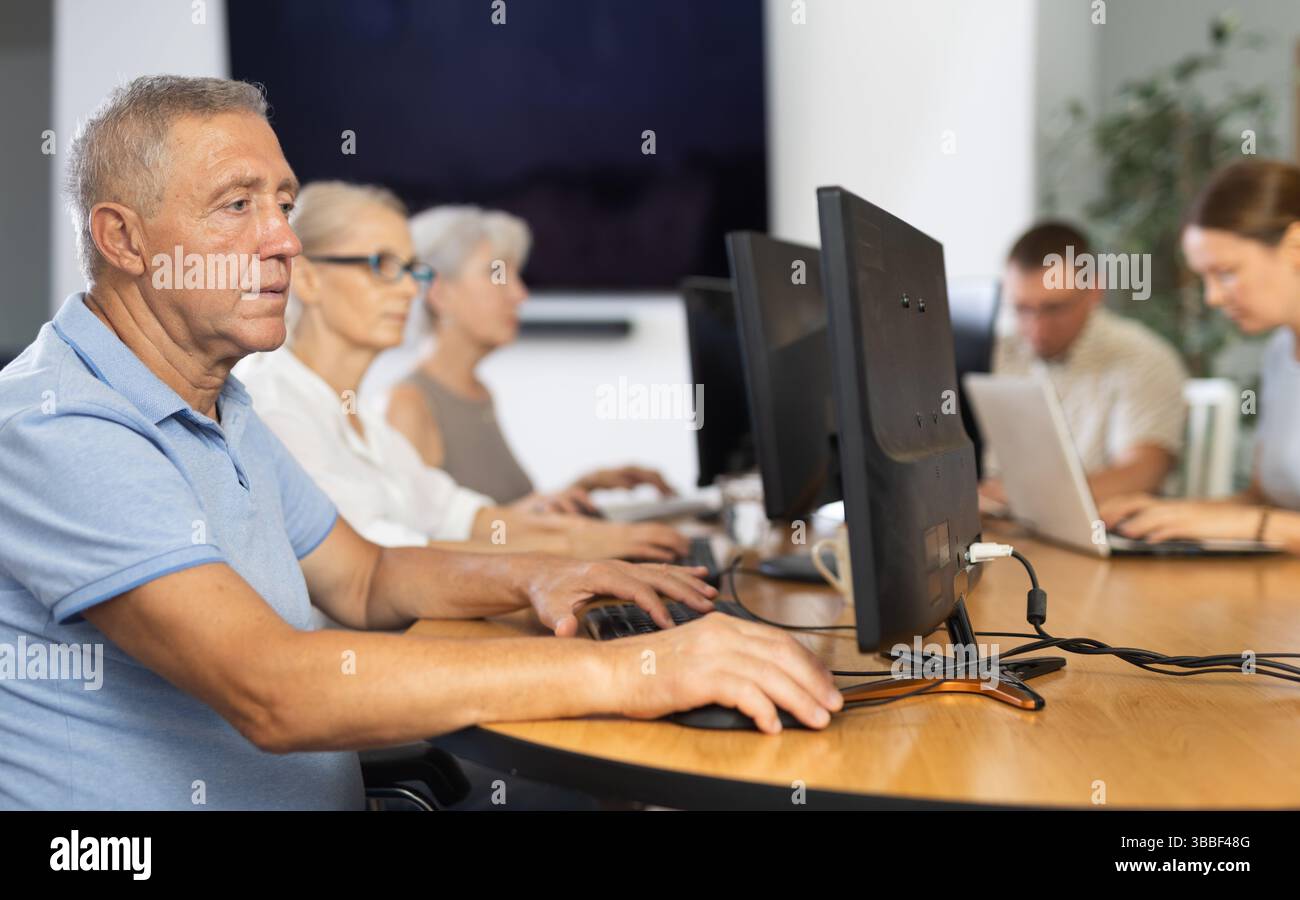 Old man learning computer programs in training room Stock Photo