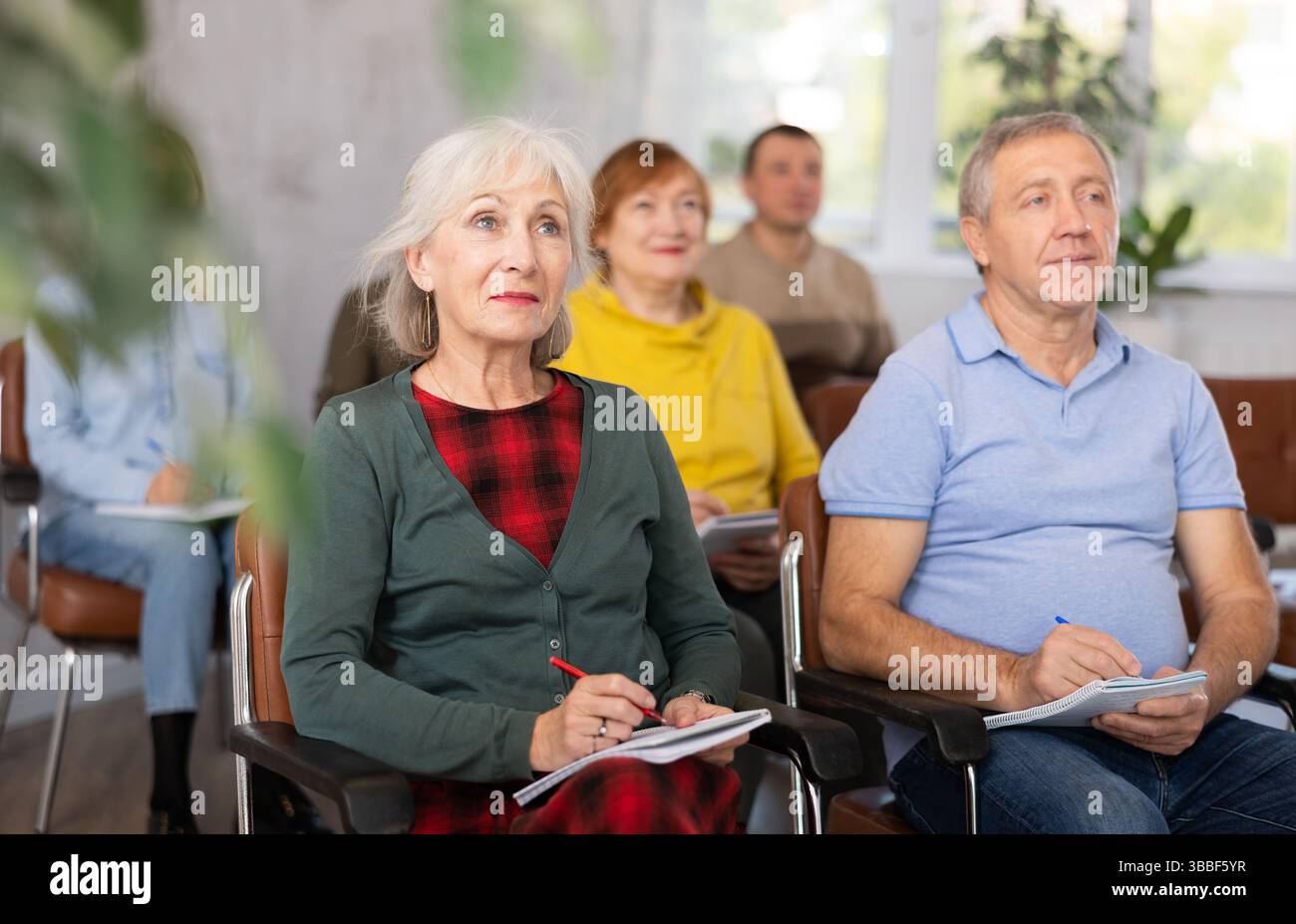 Group of older students sitting and listening at lesson Stock Photo