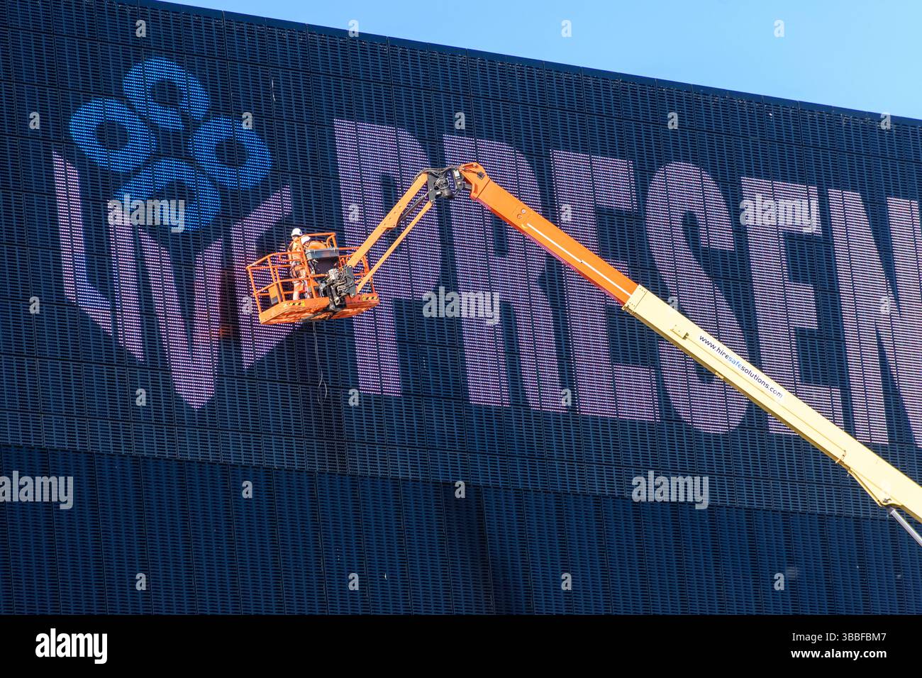 Workers on a Cherry picker (aerial platform) working on the electronic display sign at the Co-op Live Arena, Etihad Campus, Manchester, England, UK Stock Photo