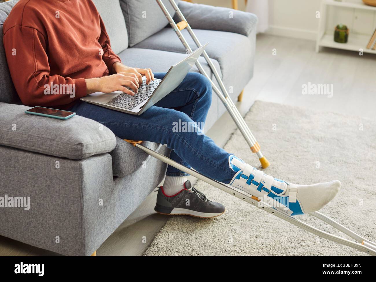 Broken leg or foot injury man working with laptop online, crutches with ...